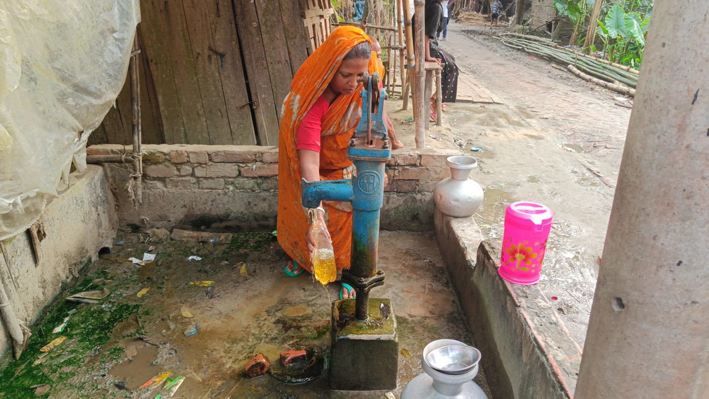 A woman filling a container at a hand pump in Gonali