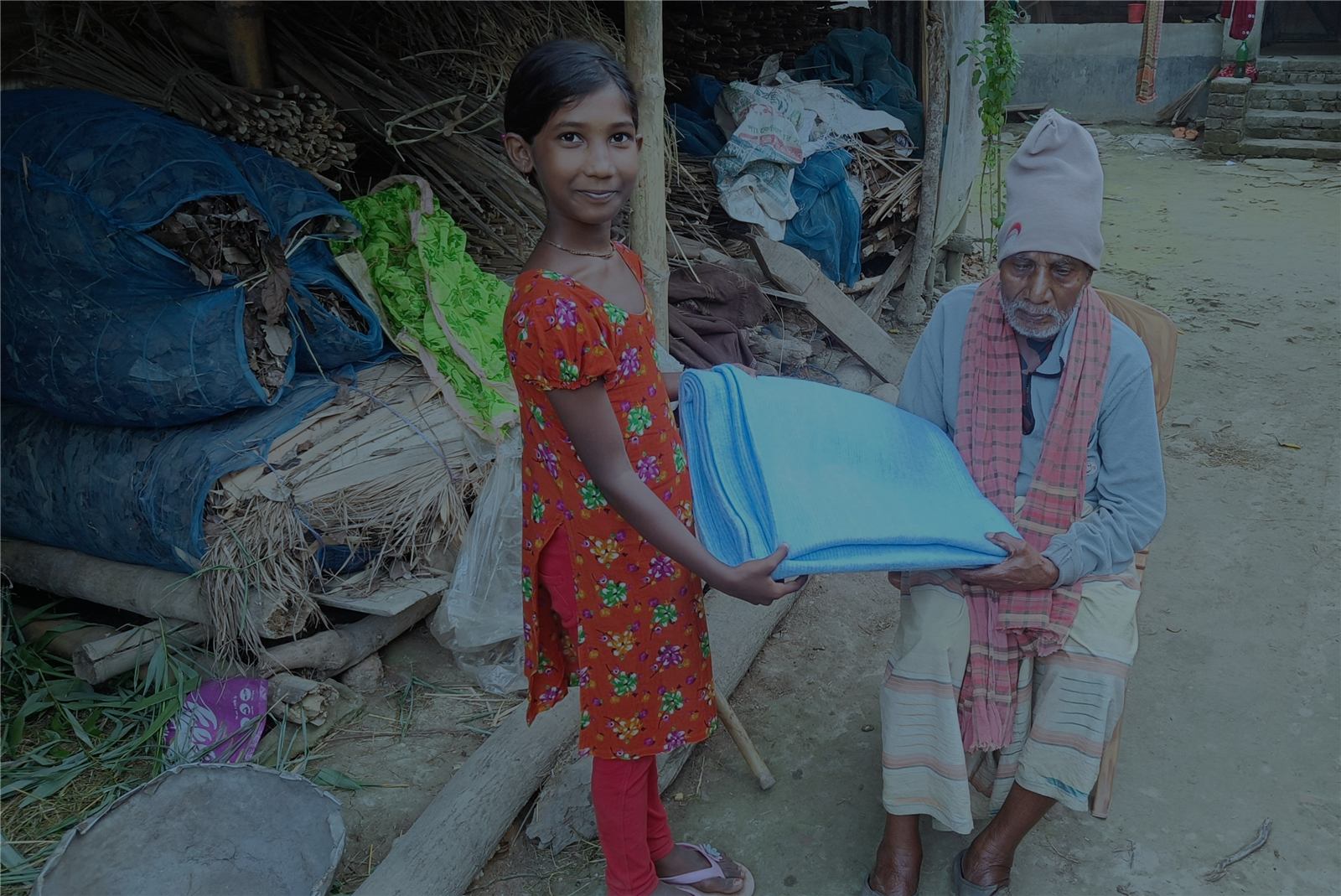 A girl handing a blanket to an older man