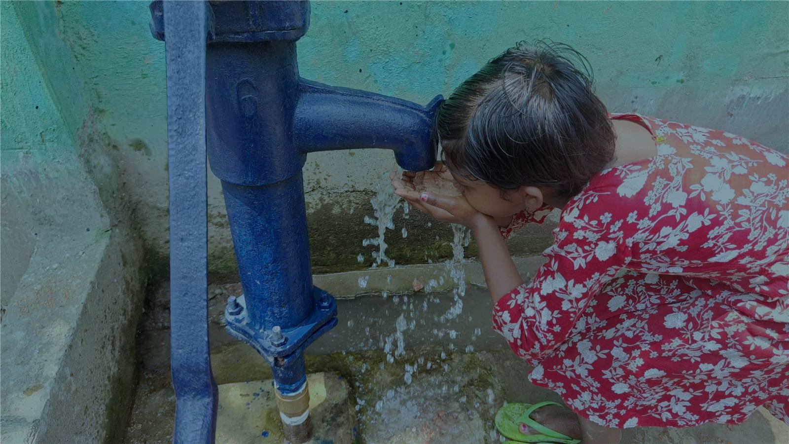 A child drinking from a water pump