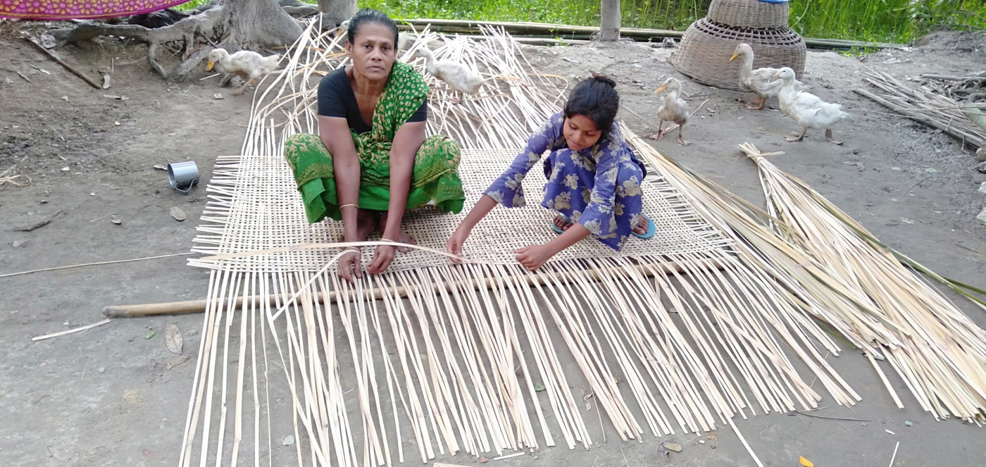 A mother and daughter weaving a bamboo mat