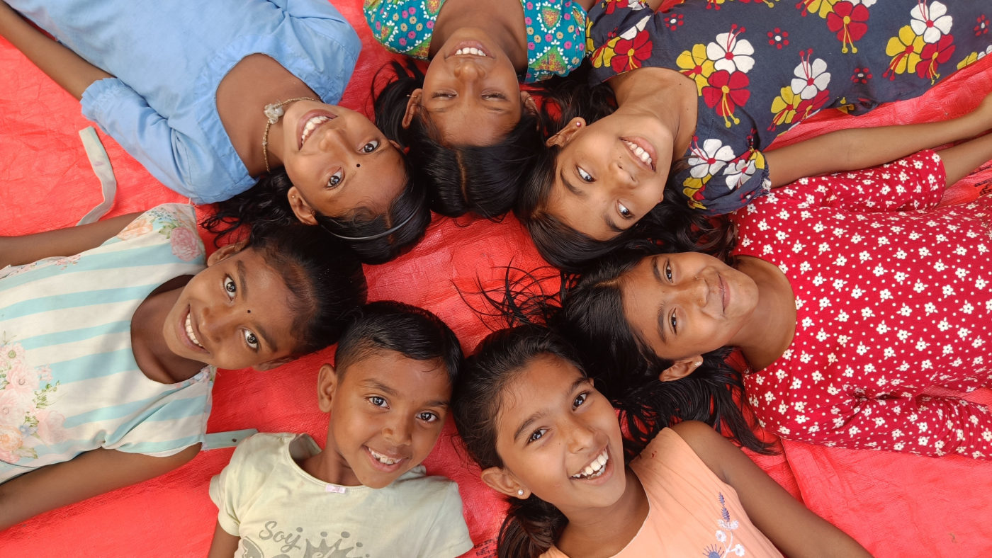 Smiling children of Gonali lying with their heads together