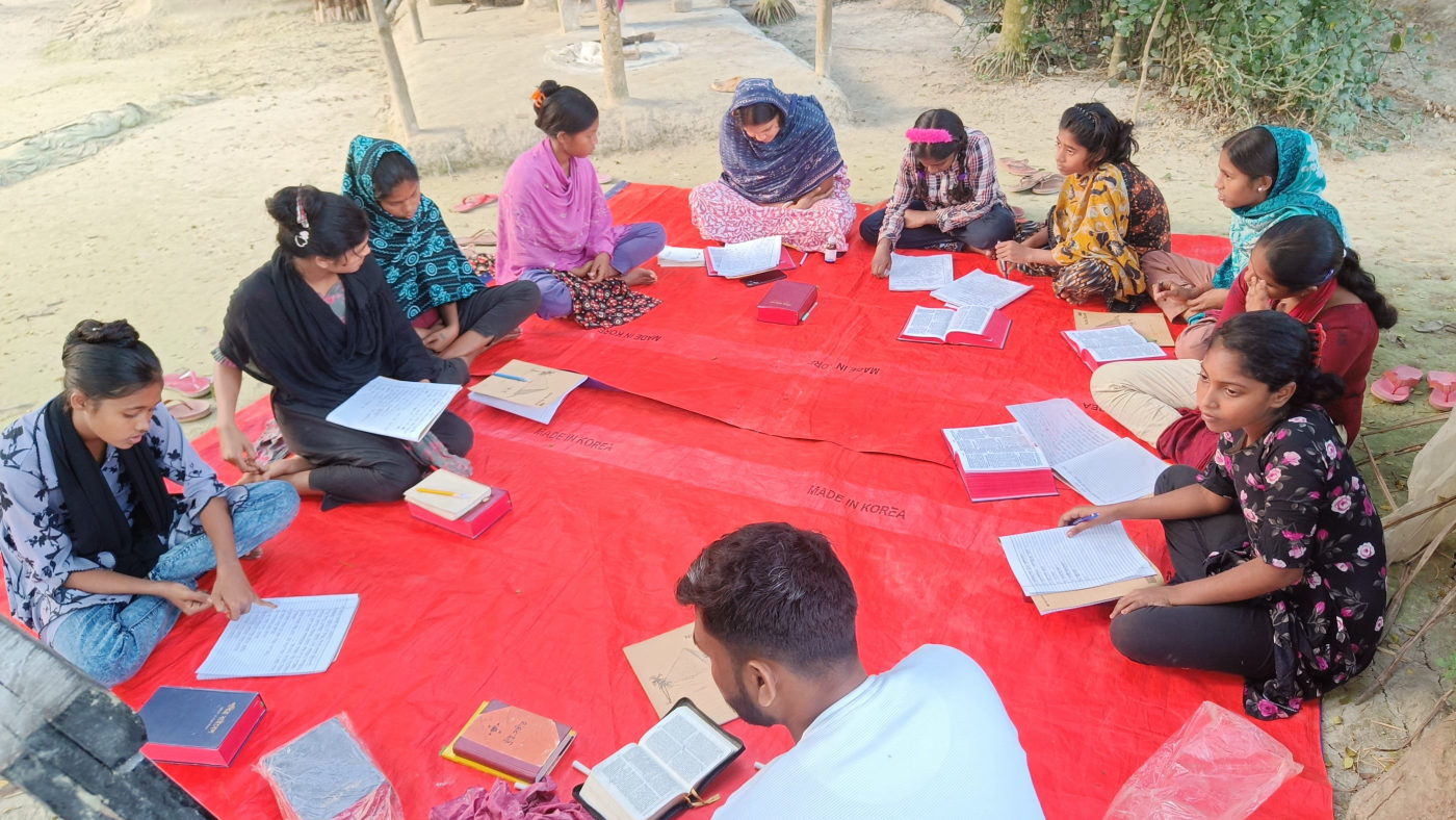 Children and volunteers reading together on a mat in Gonali